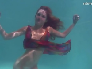 Young redhead swims in a pretty dress