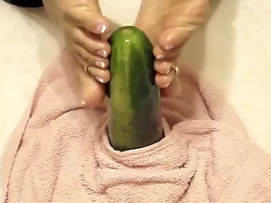 Oiled soles stroking a cucumber